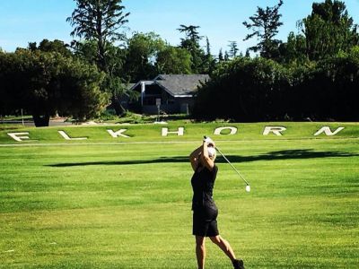 Golfer swinging in front of Elkhorn sign in greens 